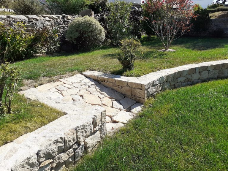 Allée en pierre naturelle et muret de pierres sèches dans un jardin du Morbihan
