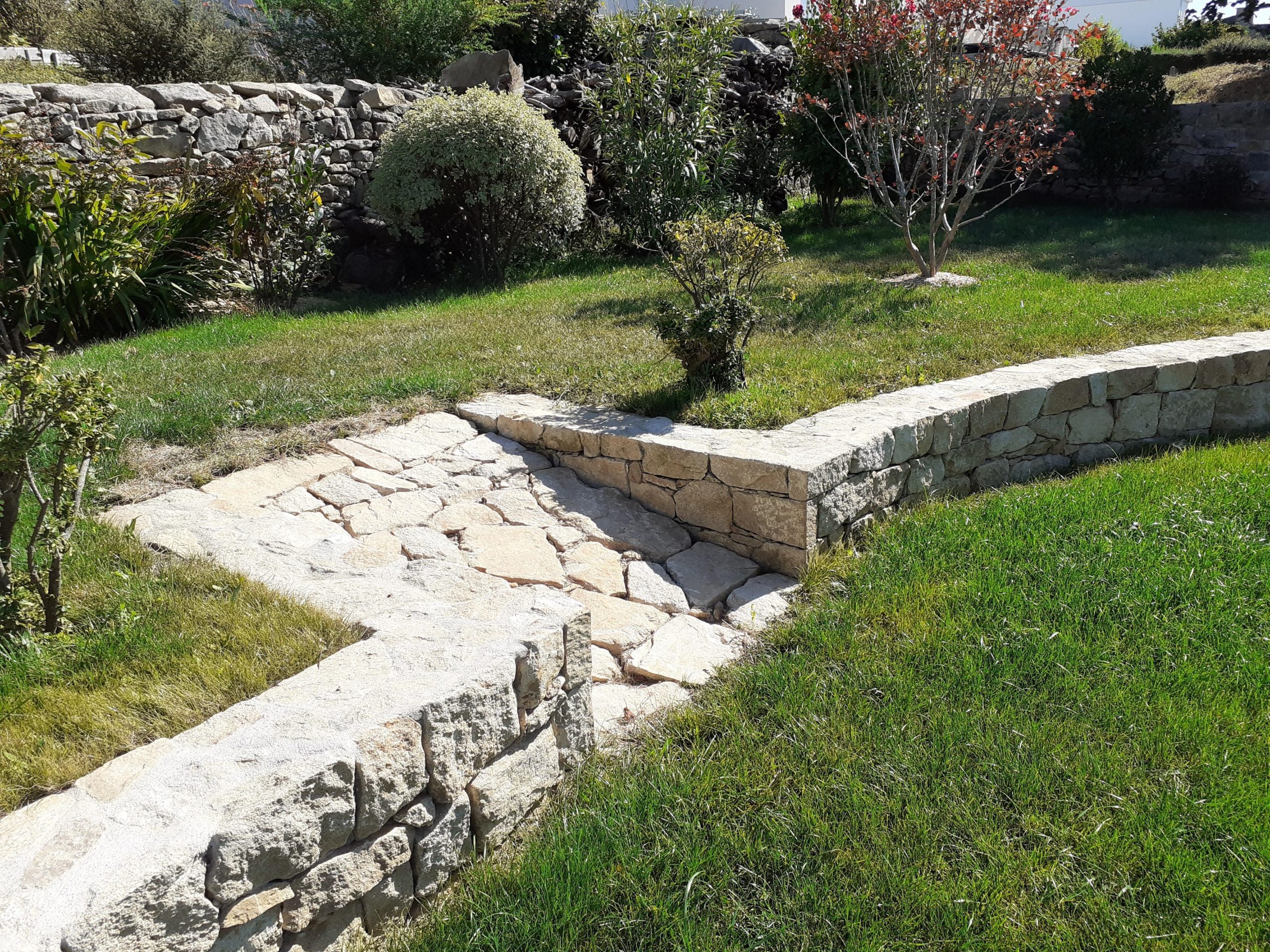 Allée en pierre naturelle et muret de pierres sèches dans un jardin du Morbihan