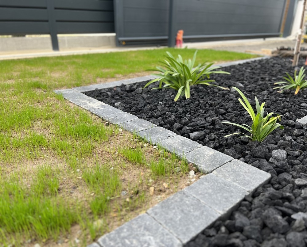 Massif paillé avec plantes vivaces et bordure en pierre, aménagement économe en eau