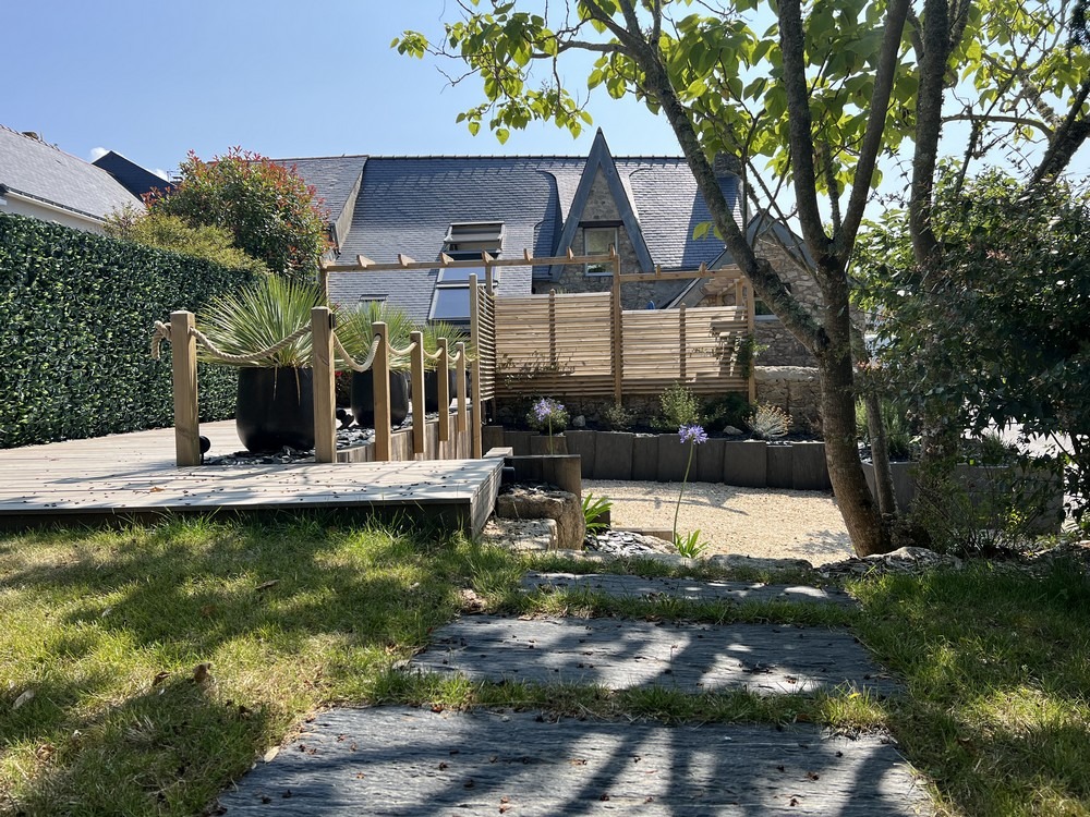 Terrasse en bois et pergola dans un jardin paysager adapté au climat breton