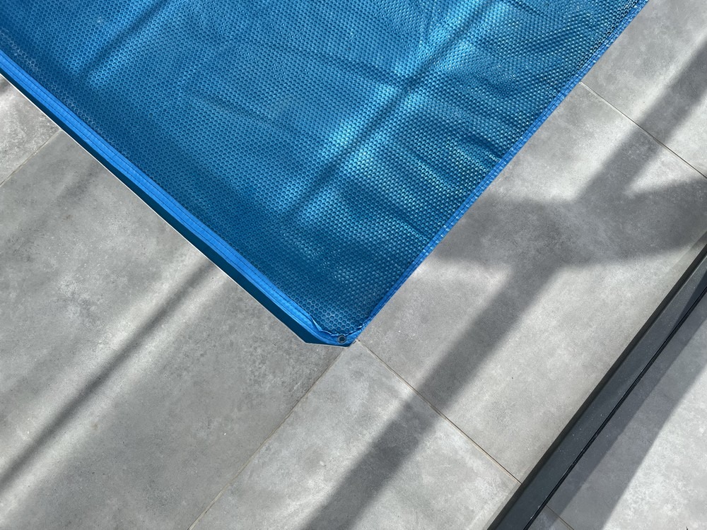 Couverture solaire bleue protégeant une piscine sur une terrasse en pierre près de Vannes